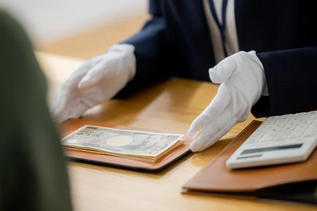 白手袋で現金を差し出す査定士と電卓